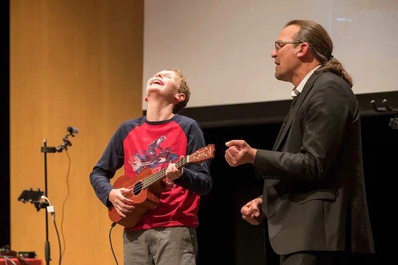 Dave Coplin on stage with an audience member playing ukulele during a keynote